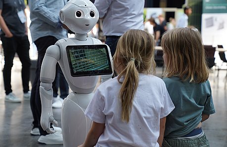 Zwei Kinder gucken sich einen Roboter auf der Summitmesse an.